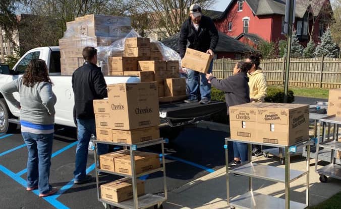 Volunteers and CIS staff members help unload a pickup truck filled with boxes of donated items.