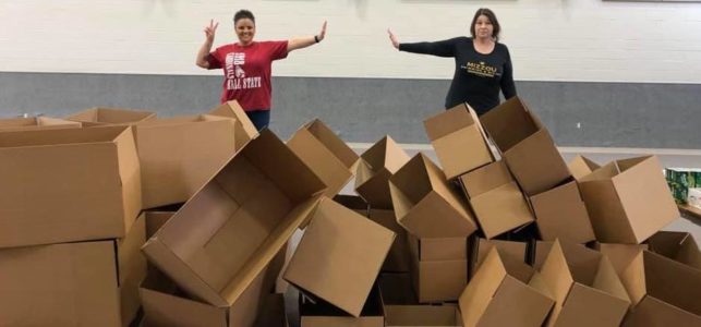 Two CIS staff members stand behind a pile of empty boxes used to distribute needed supplies to area families.